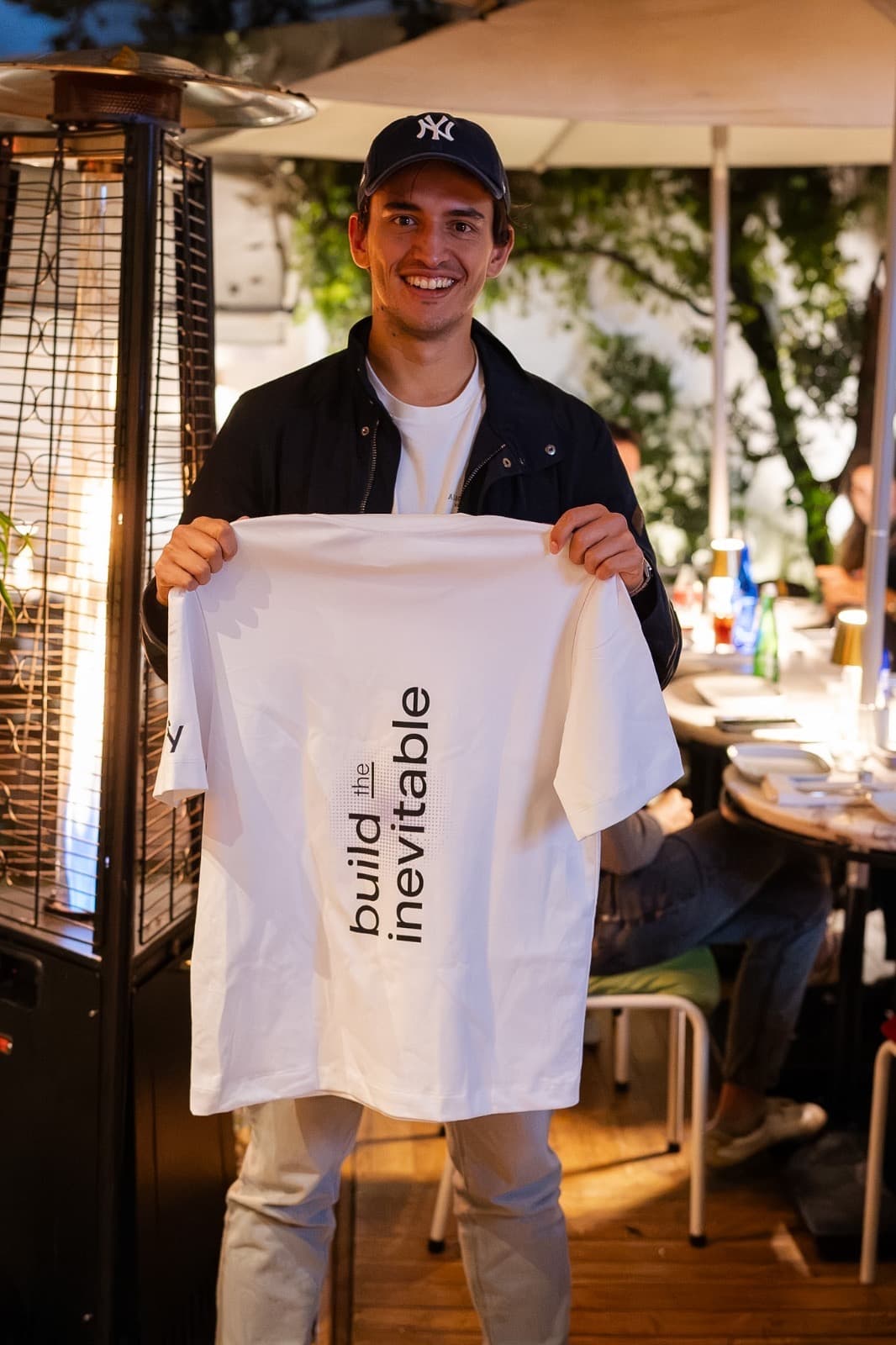 Founder holding a Build the Inevitable shirt